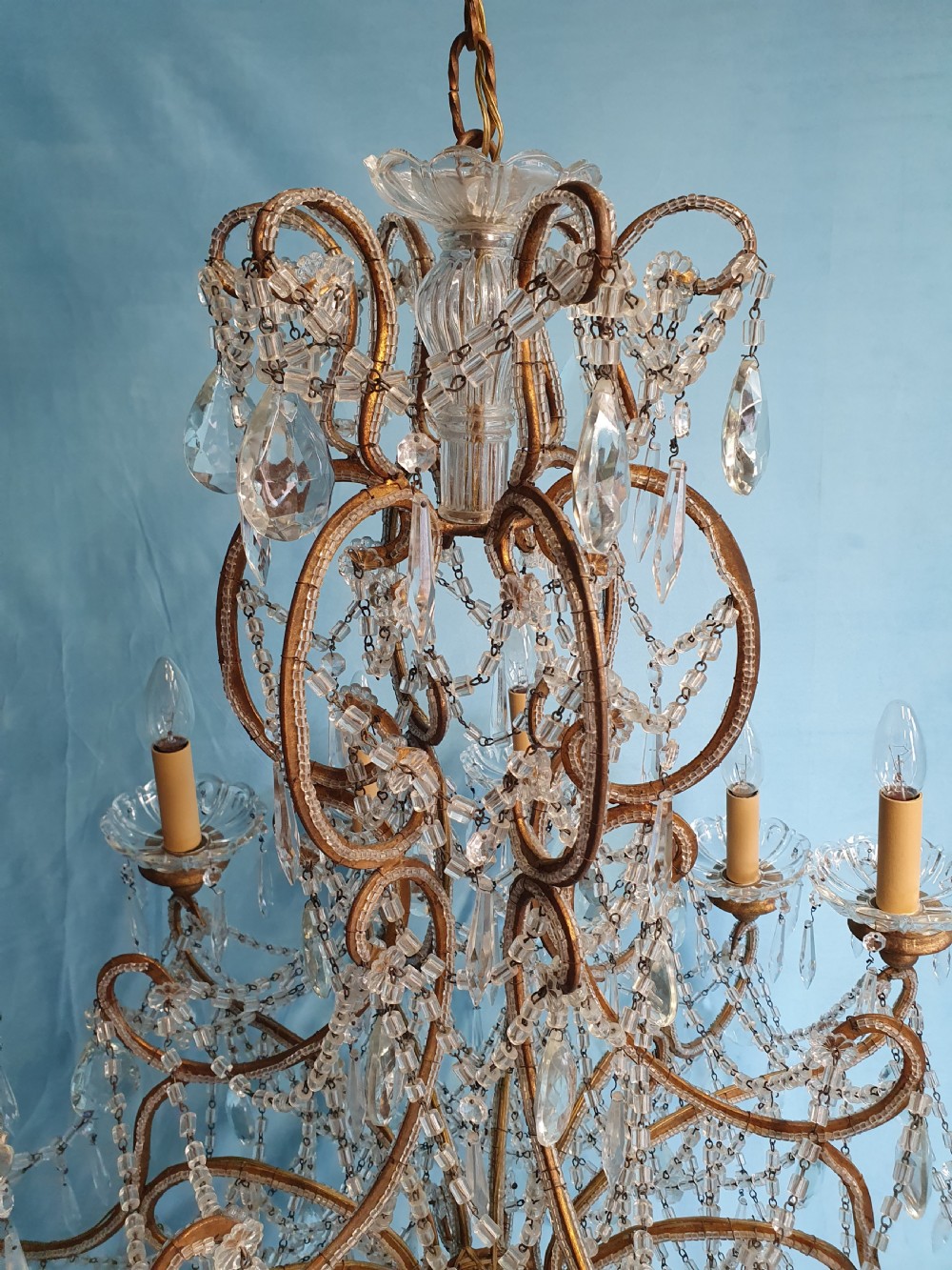 A twelve-arm gilt metal chandelier featuring cut glass crystal drops and beaded swags. View VII