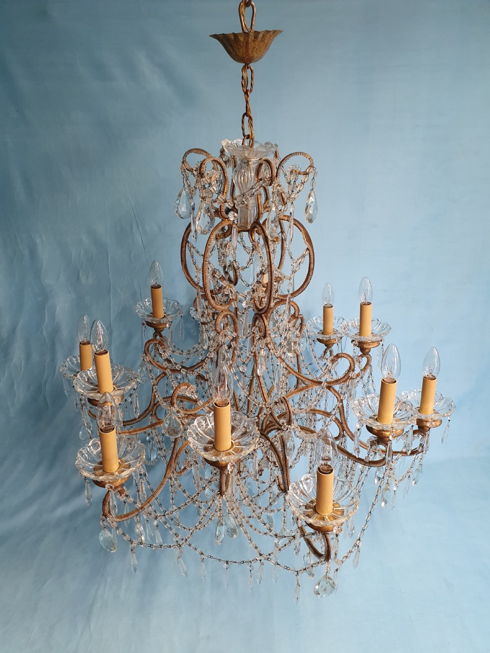 A twelve-arm gilt metal chandelier featuring cut glass crystal drops and beaded swags. View VIII