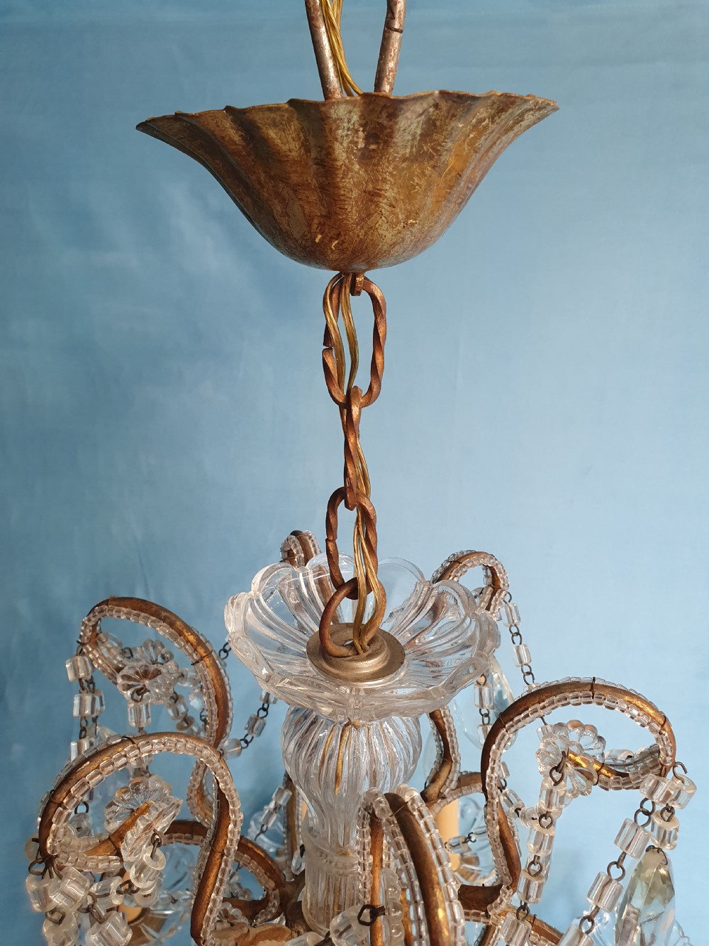 A twelve-arm gilt metal chandelier featuring cut glass crystal drops and beaded swags. View IX