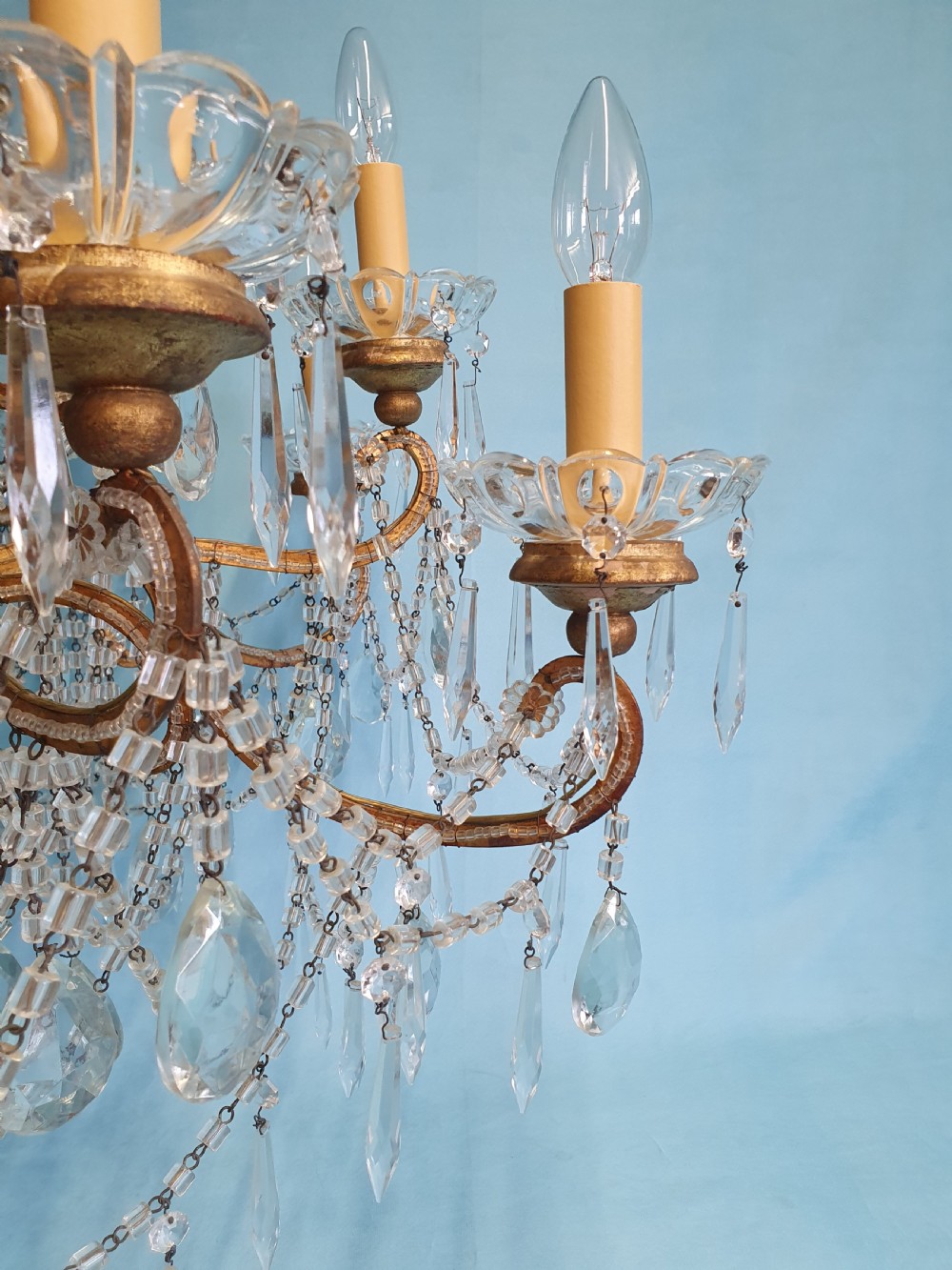 A twelve-arm gilt metal chandelier featuring cut glass crystal drops and beaded swags. View X