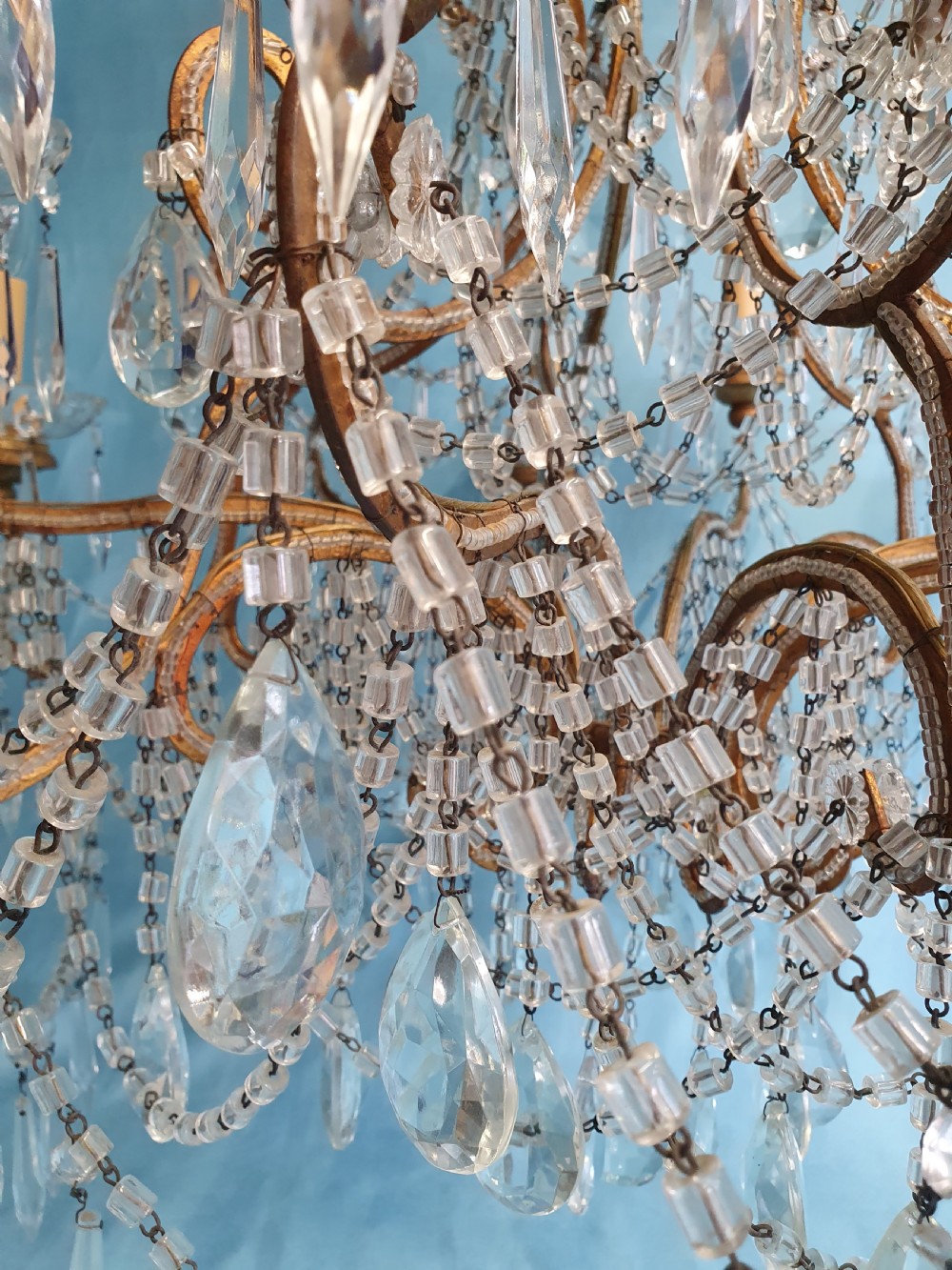 A twelve-arm gilt metal chandelier featuring cut glass crystal drops and beaded swags. View XI