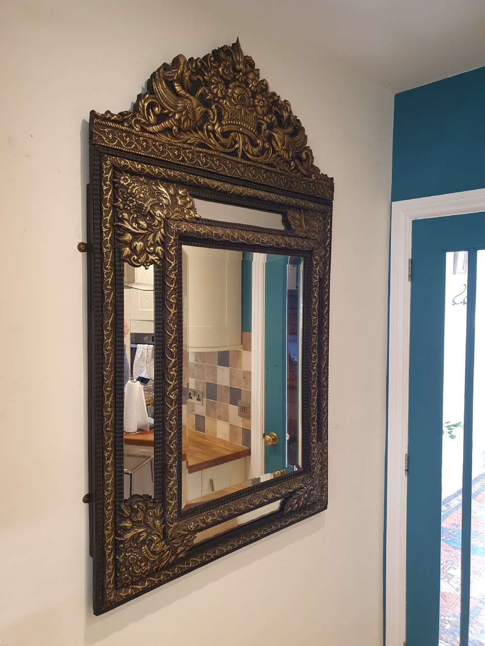 A late 19th-century rectangular Dutch wall mirror featuring an embossed brass frame with cushion moulding, intricate floral cresting, and bevelled glass.