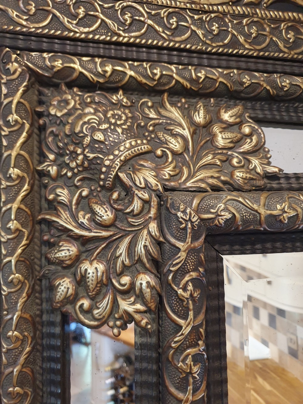 A late 19th-century rectangular Dutch wall mirror featuring an embossed brass frame with cushion moulding, intricate floral cresting, and bevelled glass. View III