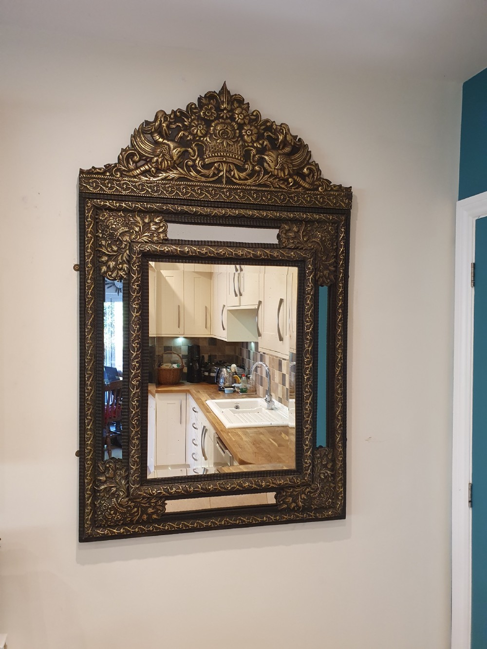A late 19th-century rectangular Dutch wall mirror featuring an embossed brass frame with cushion moulding, intricate floral cresting, and bevelled glass. View V