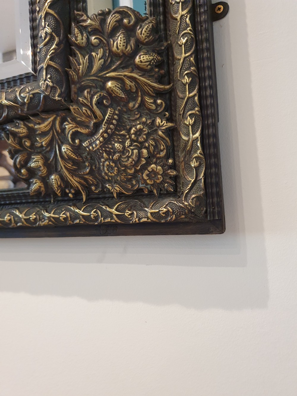 A late 19th-century rectangular Dutch wall mirror featuring an embossed brass frame with cushion moulding, intricate floral cresting, and bevelled glass. View VI