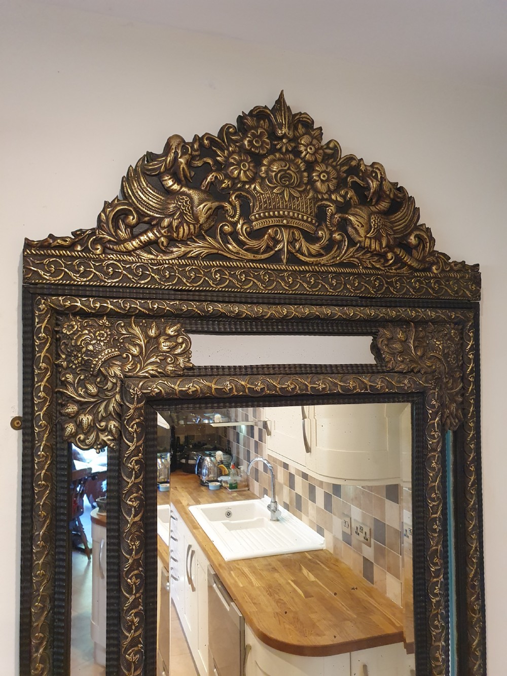 A late 19th-century rectangular Dutch wall mirror featuring an embossed brass frame with cushion moulding, intricate floral cresting, and bevelled glass. View VII