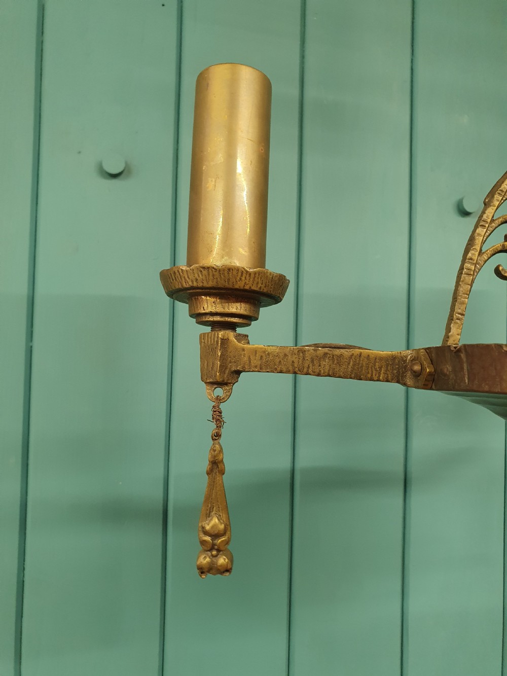 An Art Deco gilt brass three-arm chandelier featuring geometric central columns, candle-style bulb holders, and dangling teardrop accents. View II