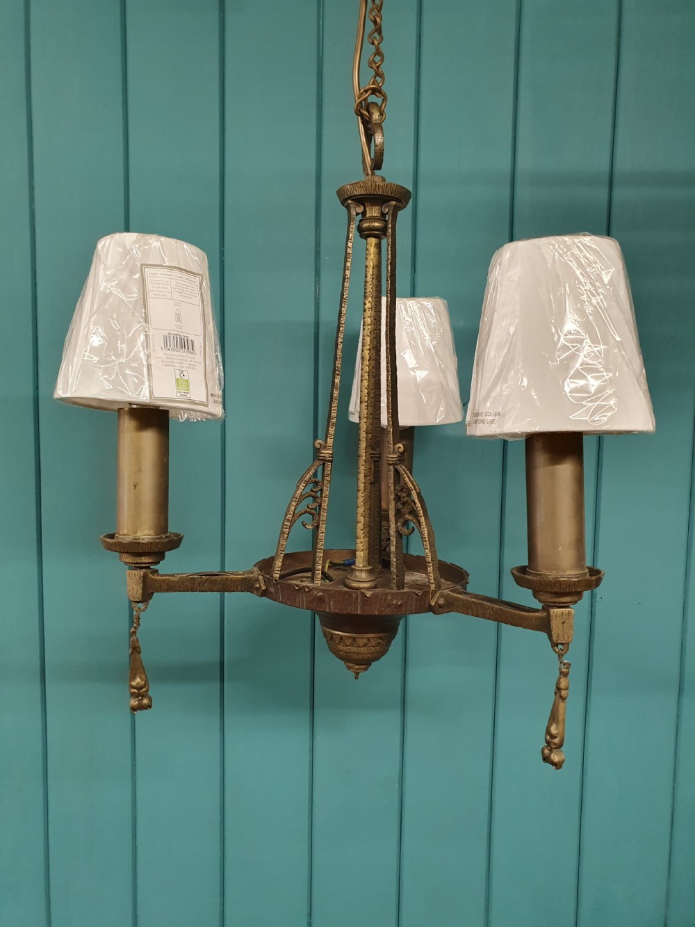 An Art Deco gilt brass three-arm chandelier featuring geometric central columns, candle-style bulb holders, and dangling teardrop accents. View III