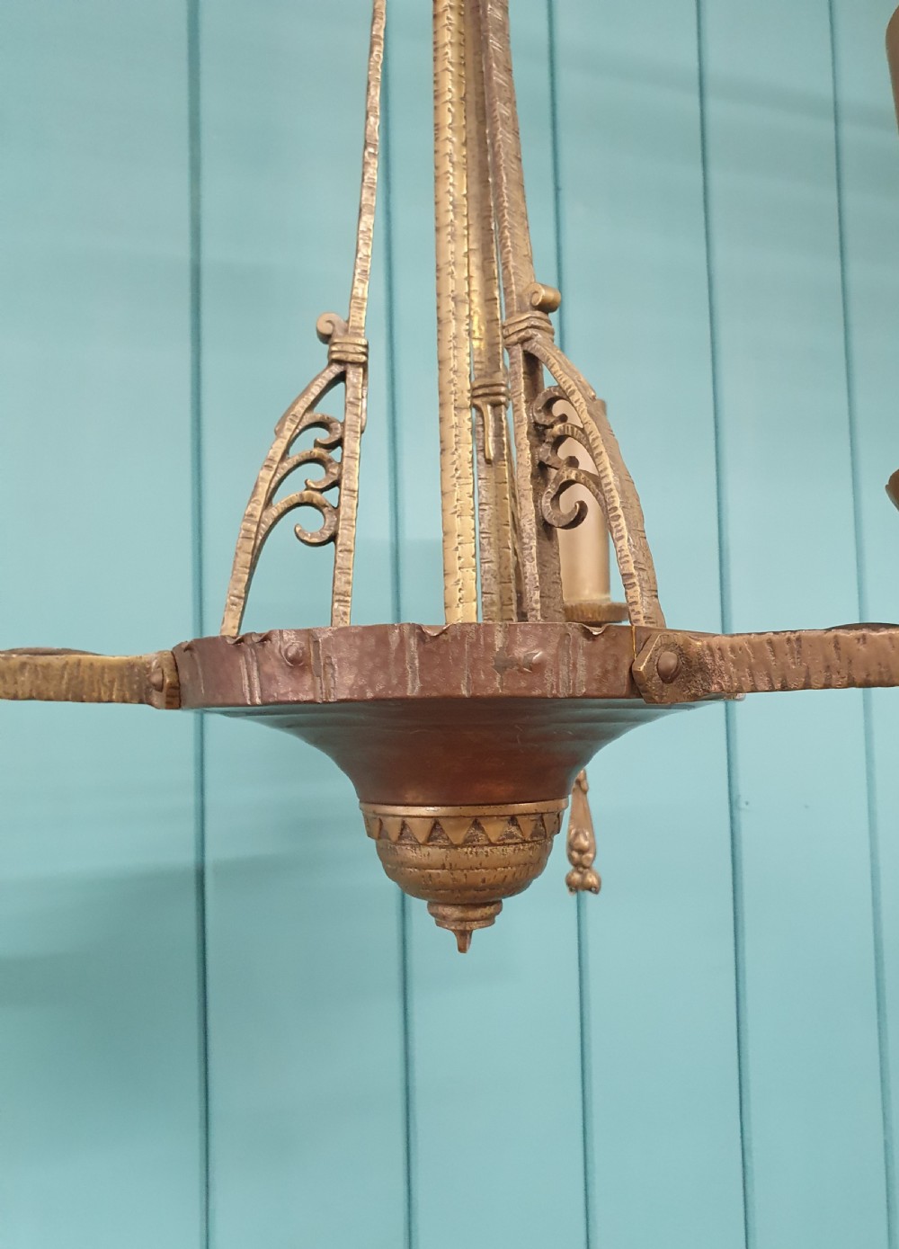 An Art Deco gilt brass three-arm chandelier featuring geometric central columns, candle-style bulb holders, and dangling teardrop accents. View IV