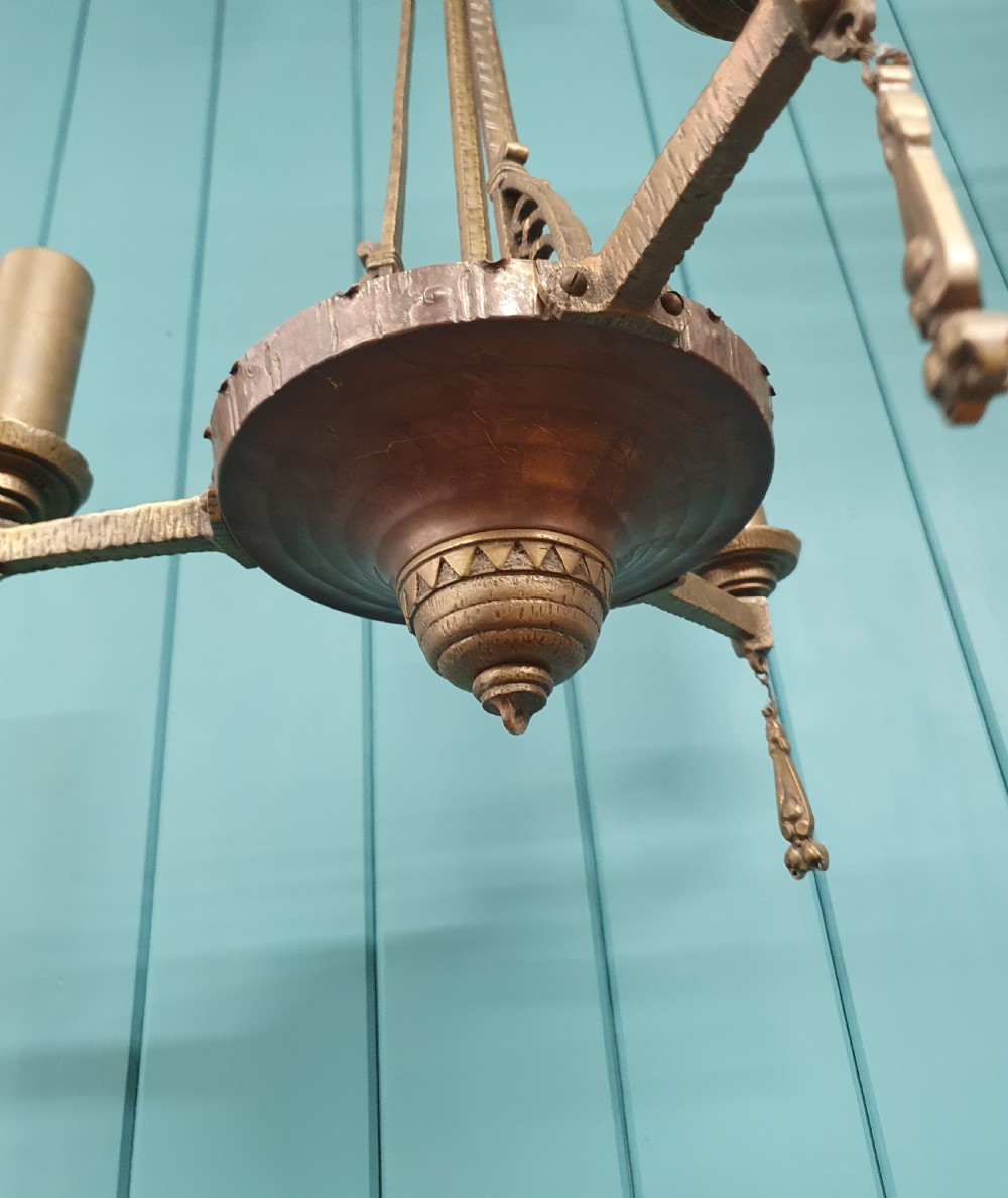 An Art Deco gilt brass three-arm chandelier featuring geometric central columns, candle-style bulb holders, and dangling teardrop accents. View V