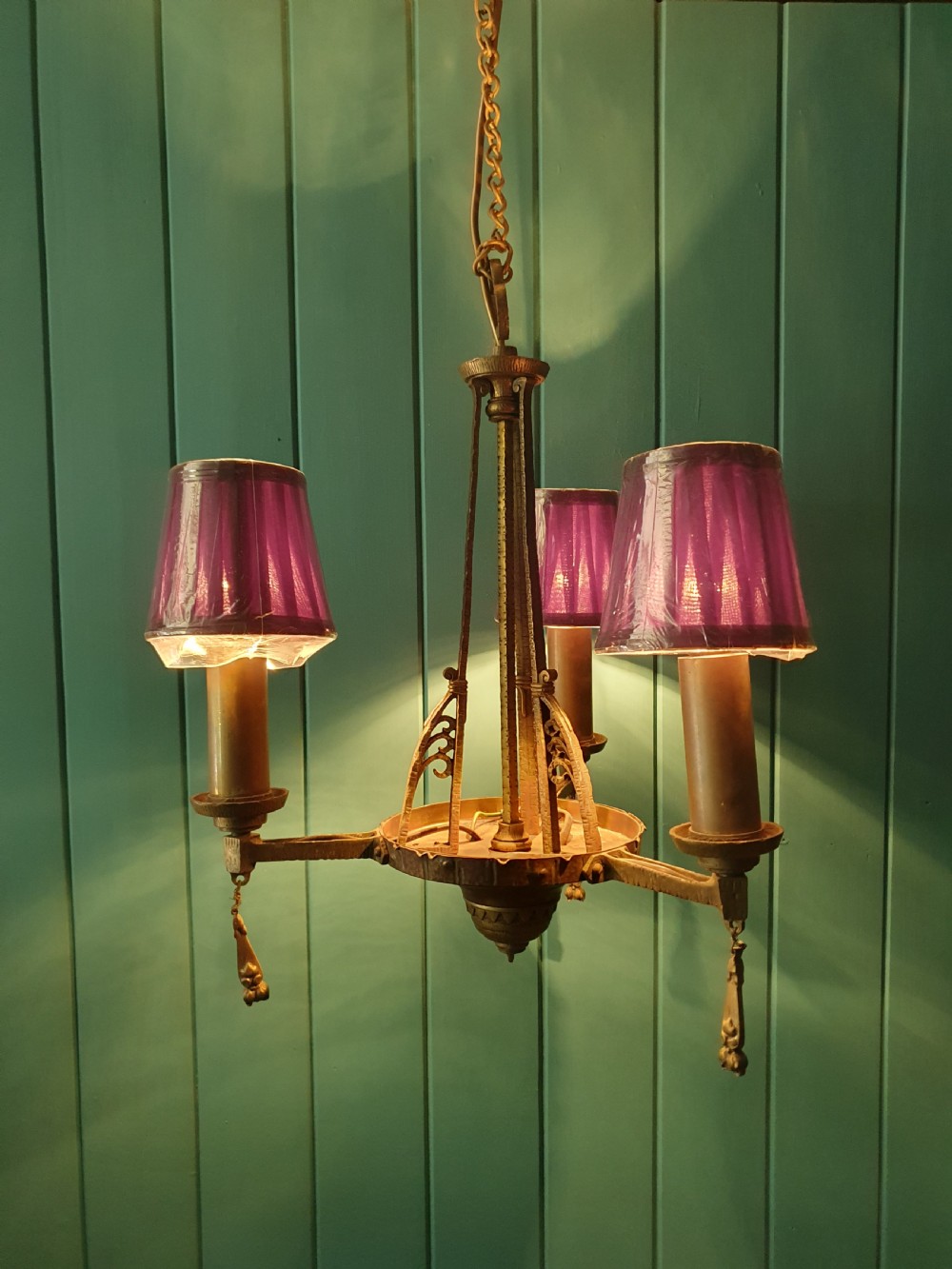 An Art Deco gilt brass three-arm chandelier featuring geometric central columns, candle-style bulb holders, and dangling teardrop accents. View IX