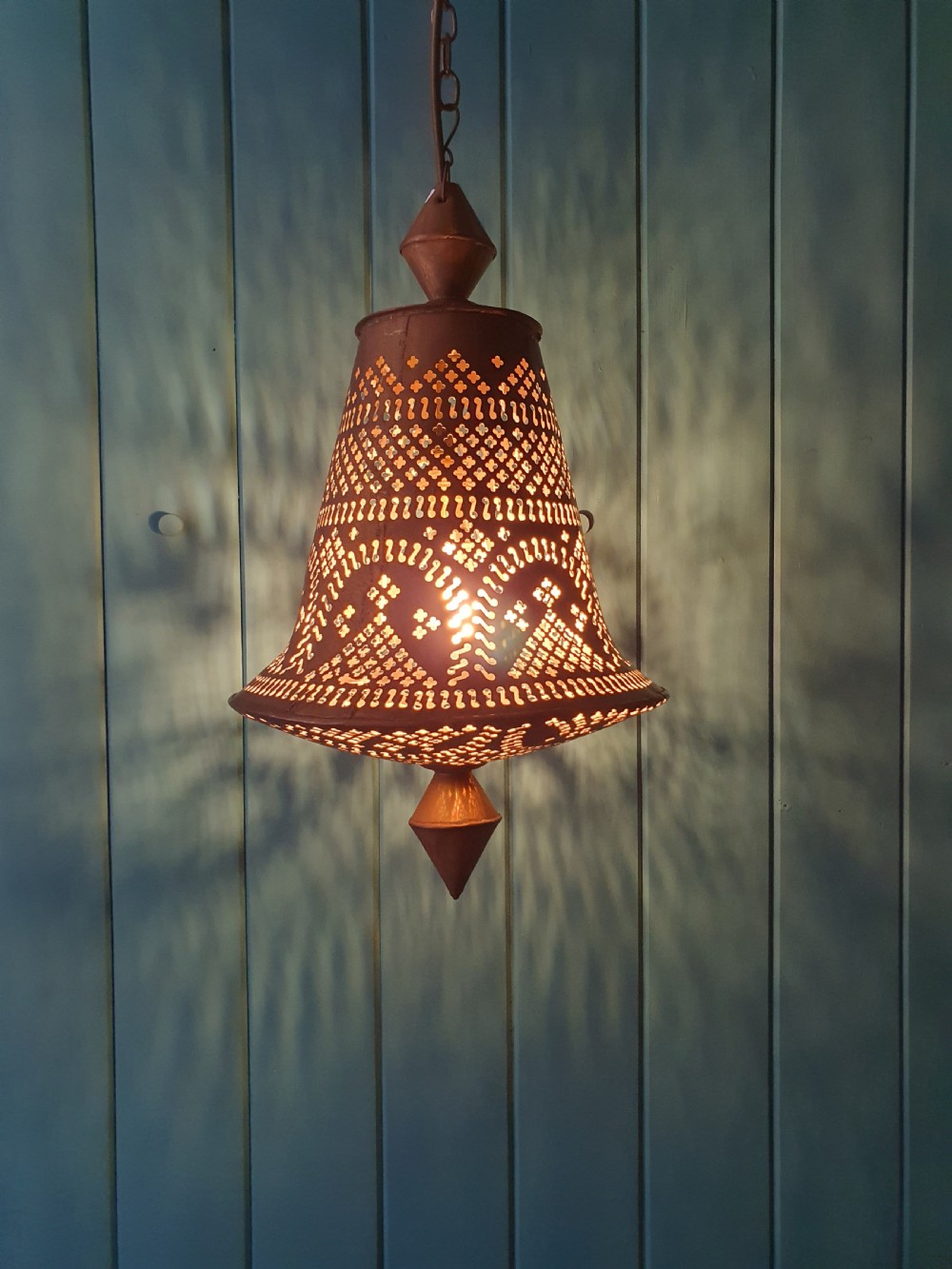 A flared bell-shaped pierced brass pendant light with geometric reticulated patterns suspended from a brass chain. View III