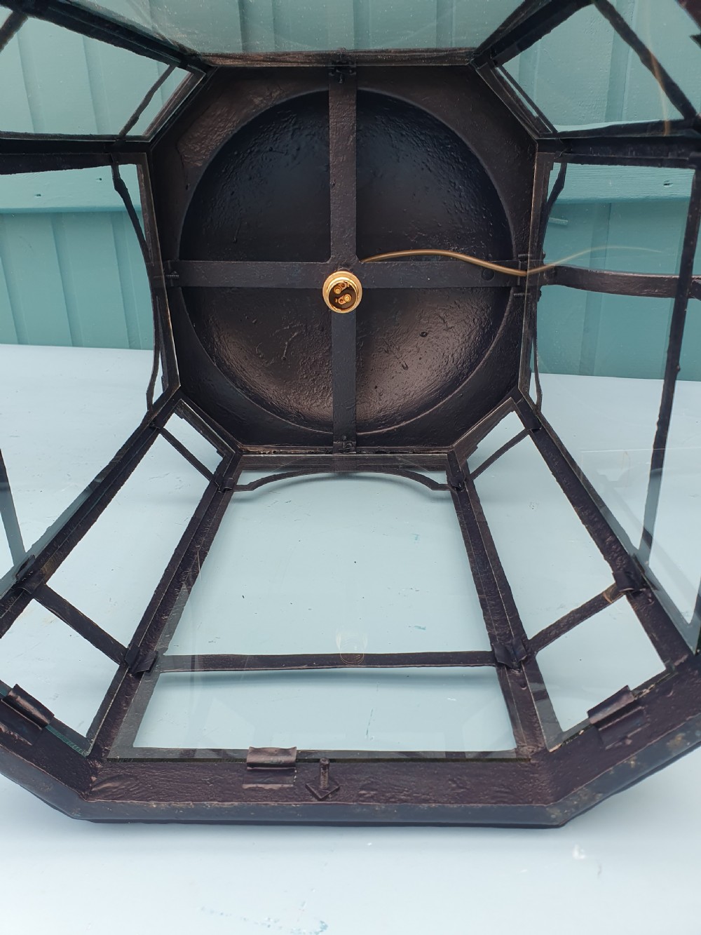 A pair of early 20th-century octagonal black wrought iron wall lanterns featuring clear glass panels, arched tracery, scrollwork brackets, and brass finials. View II