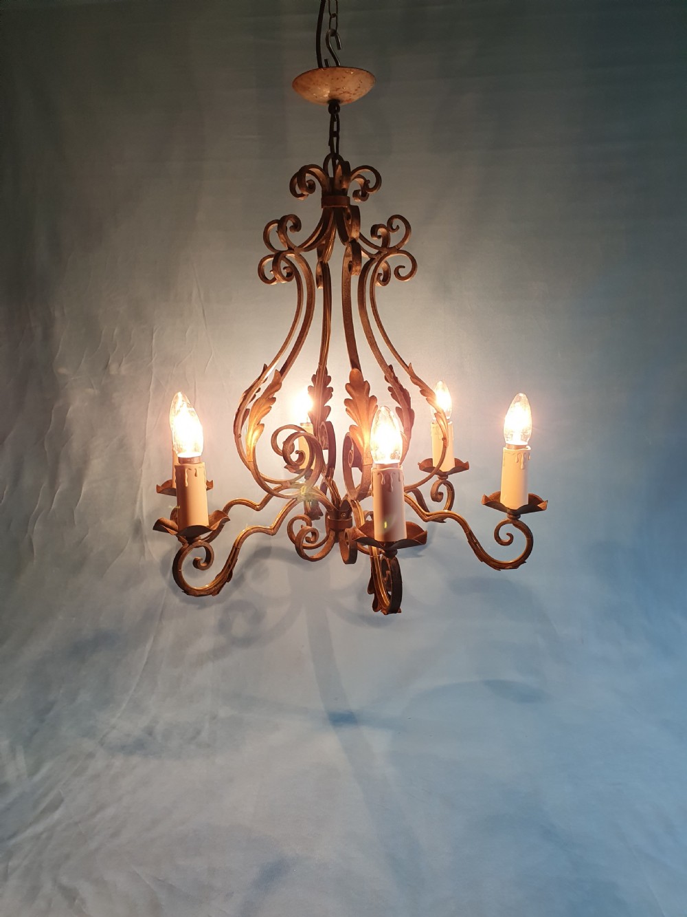 A dark green six-arm wrought steel chandelier with scrollwork arms, candle sleeves, and dark lampshades. View II
