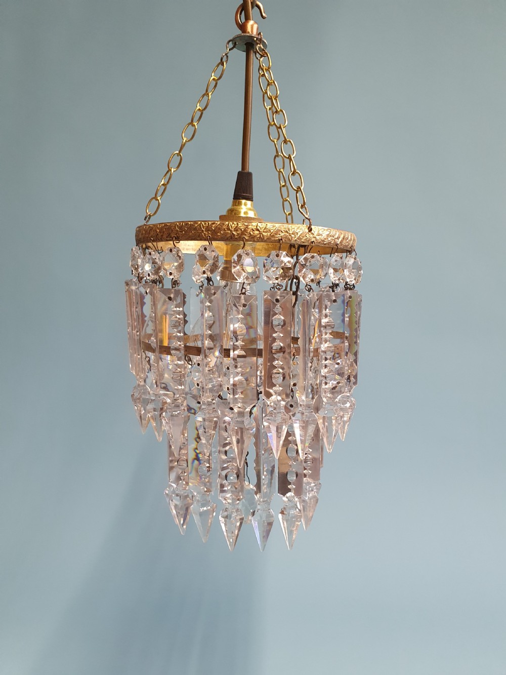 An early 20th-century brass ceiling pendant featuring tiered rows of faceted glass crystal droplets suspended by metal chains. View III