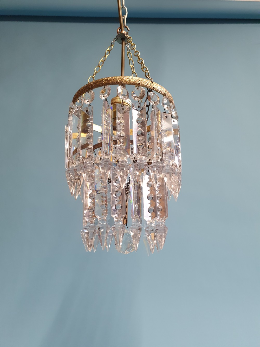 An early 20th-century brass ceiling pendant featuring tiered rows of faceted glass crystal droplets suspended by metal chains. View V
