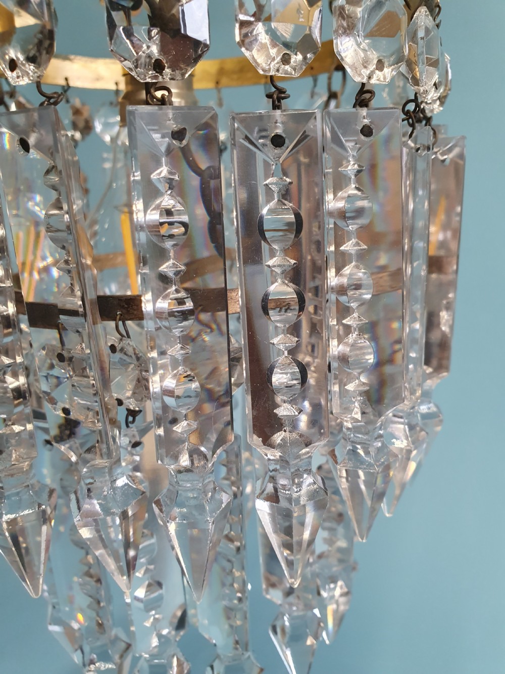 An early 20th-century brass ceiling pendant featuring tiered rows of faceted glass crystal droplets suspended by metal chains. View VI