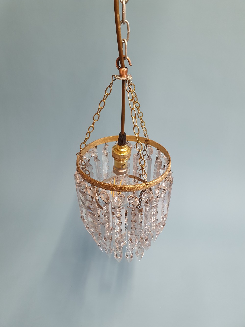 An early 20th-century brass ceiling pendant featuring tiered rows of faceted glass crystal droplets suspended by metal chains. View IX
