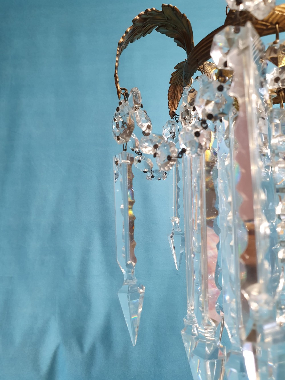 An early 20th-century small brass chandelier featuring acanthus leaf scroll arms suspending multiple tiers of clear faceted crystal prisms and droplets. View VII