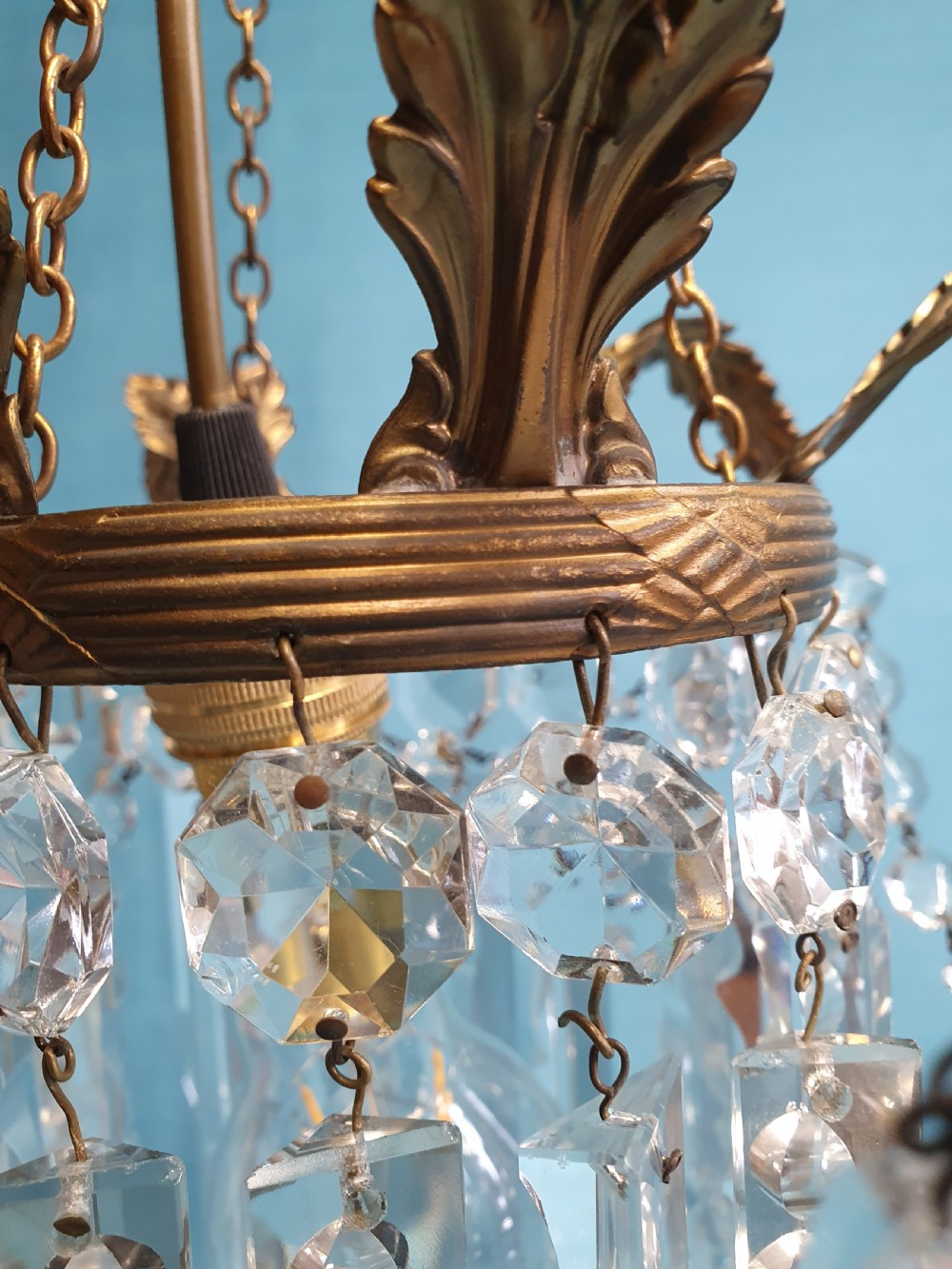 An early 20th-century small brass chandelier featuring acanthus leaf scroll arms suspending multiple tiers of clear faceted crystal prisms and droplets. View VIII
