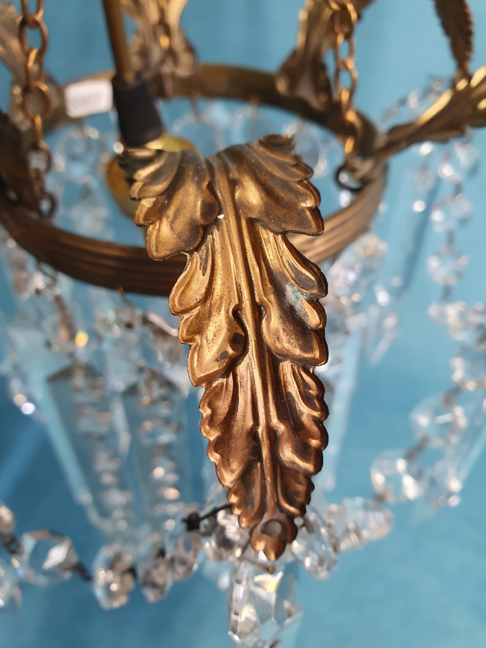 An early 20th-century small brass chandelier featuring acanthus leaf scroll arms suspending multiple tiers of clear faceted crystal prisms and droplets. View IX