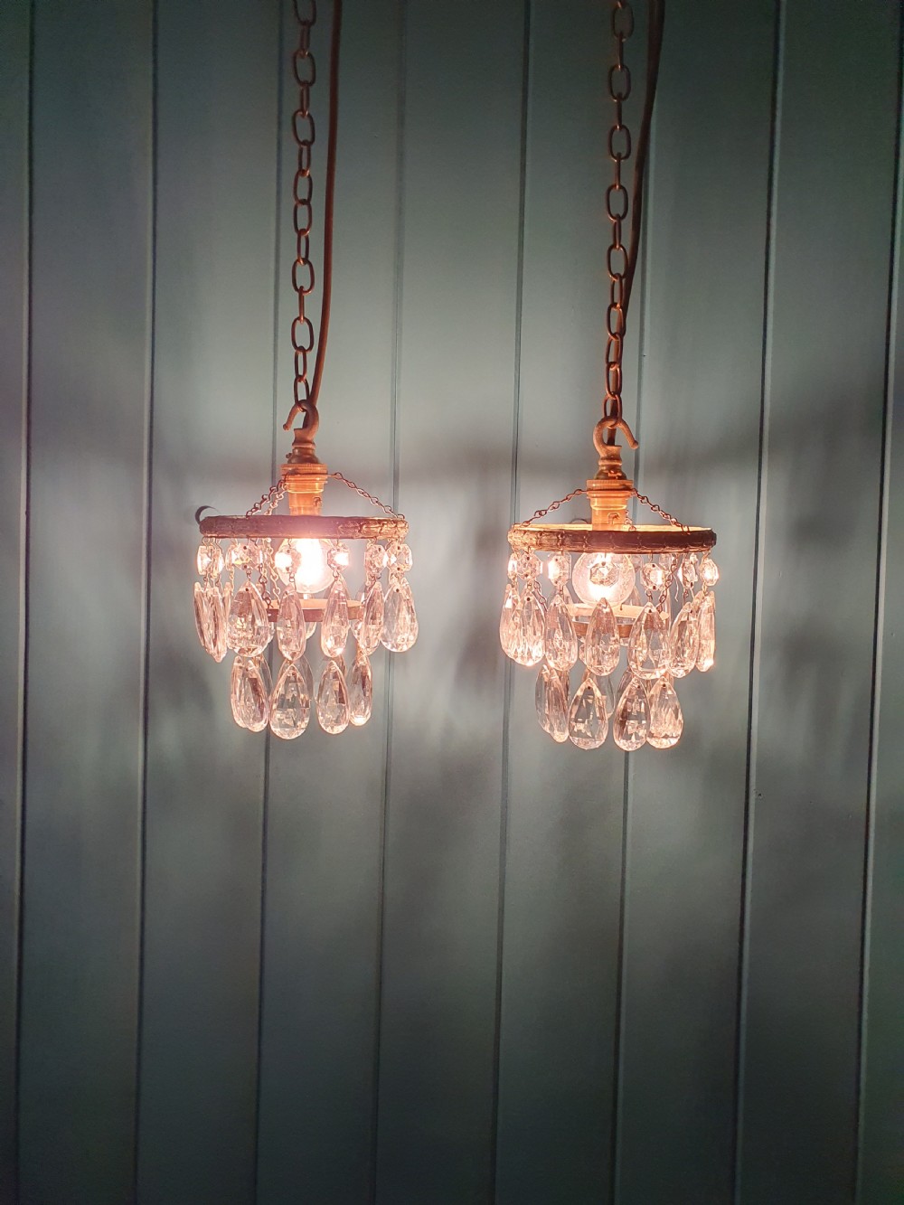 A pair of small early 20th-century brass ceiling pendant chandeliers featuring tiers of hanging faceted clear crystal droplets. View II