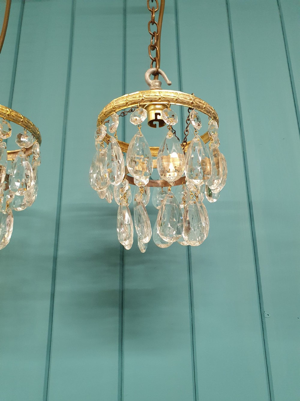 A pair of small early 20th-century brass ceiling pendant chandeliers featuring tiers of hanging faceted clear crystal droplets. View IV