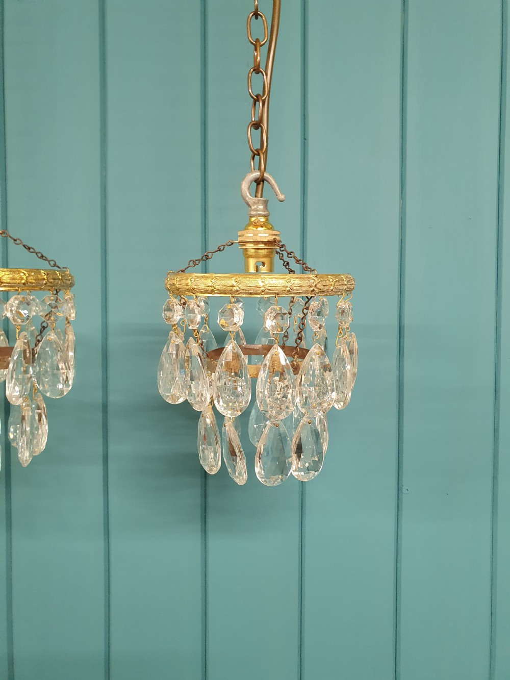 A pair of small early 20th-century brass ceiling pendant chandeliers featuring tiers of hanging faceted clear crystal droplets. View VI