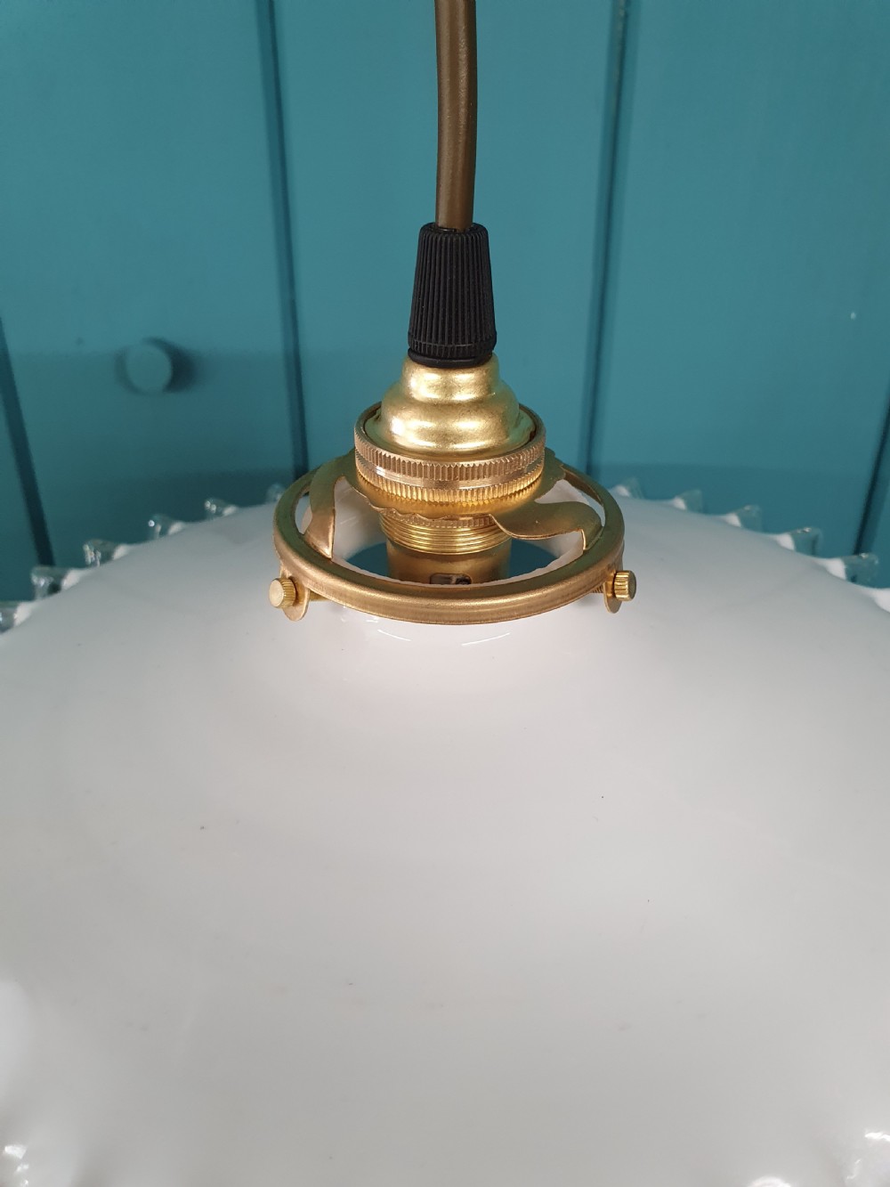 A white opaline glass pendant lampshade featuring a clear crimped frill edge suspended from a brass fixture. View VI