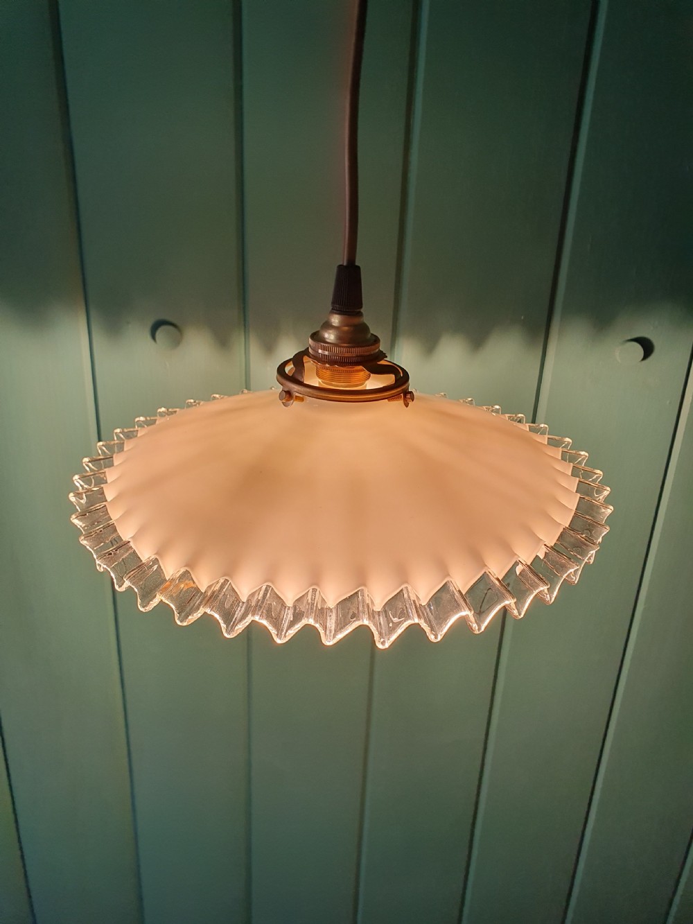 A white opaline glass pendant lampshade featuring a clear crimped frill edge suspended from a brass fixture. View VII