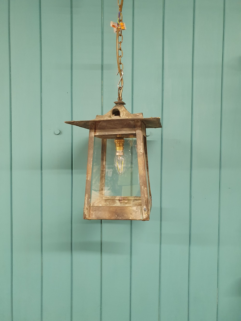 An early 20th-century patinated brass pendant lantern with clear glass side panels suspended by a chain.