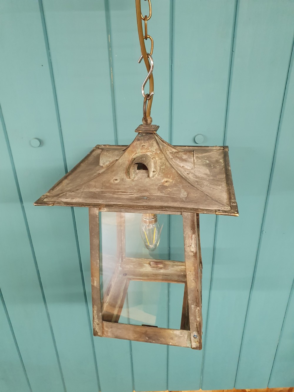 An early 20th-century patinated brass pendant lantern with clear glass side panels suspended by a chain. View III