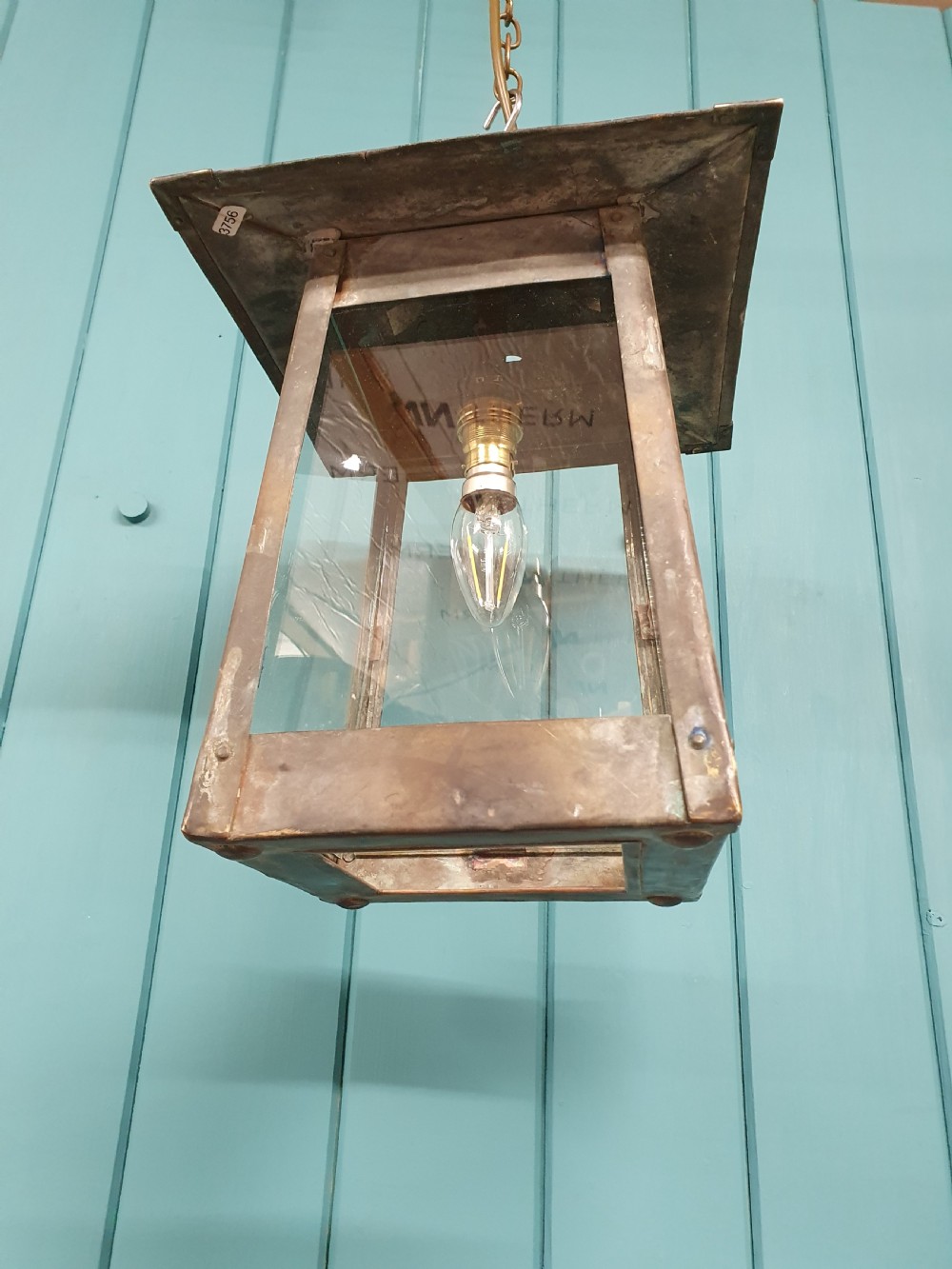 An early 20th-century patinated brass pendant lantern with clear glass side panels suspended by a chain. View V