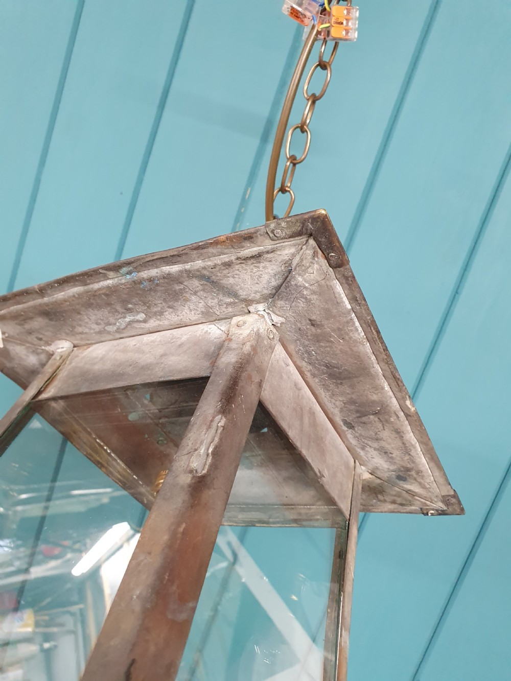 An early 20th-century patinated brass pendant lantern with clear glass side panels suspended by a chain. View VI