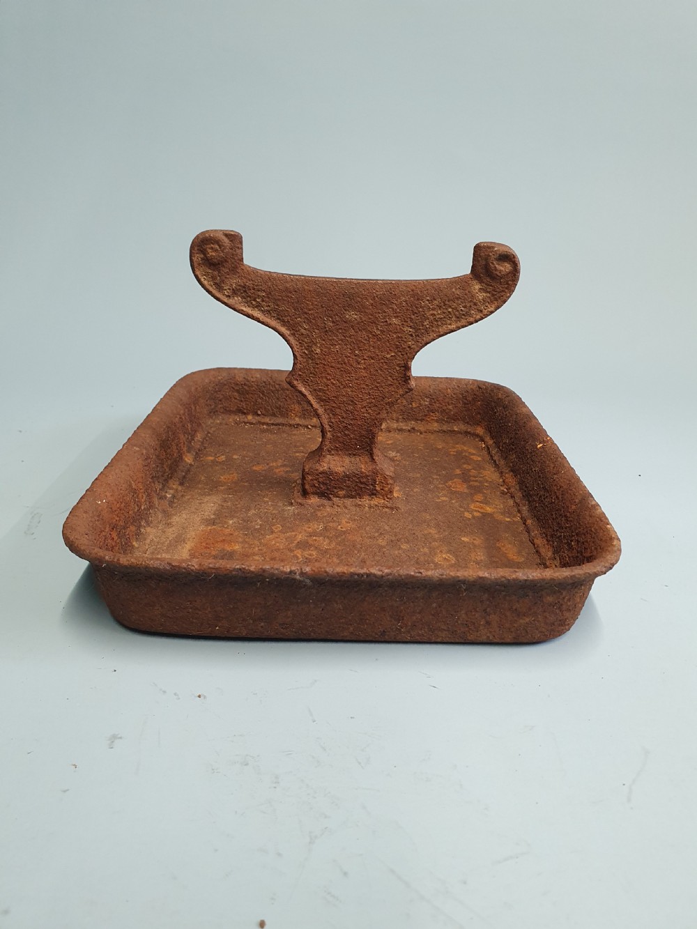 A late nineteenth-century cast iron boot scraper featuring a rectangular drip tray base and a scroll-detailed scraping blade with heavy rusted patina. View IV
