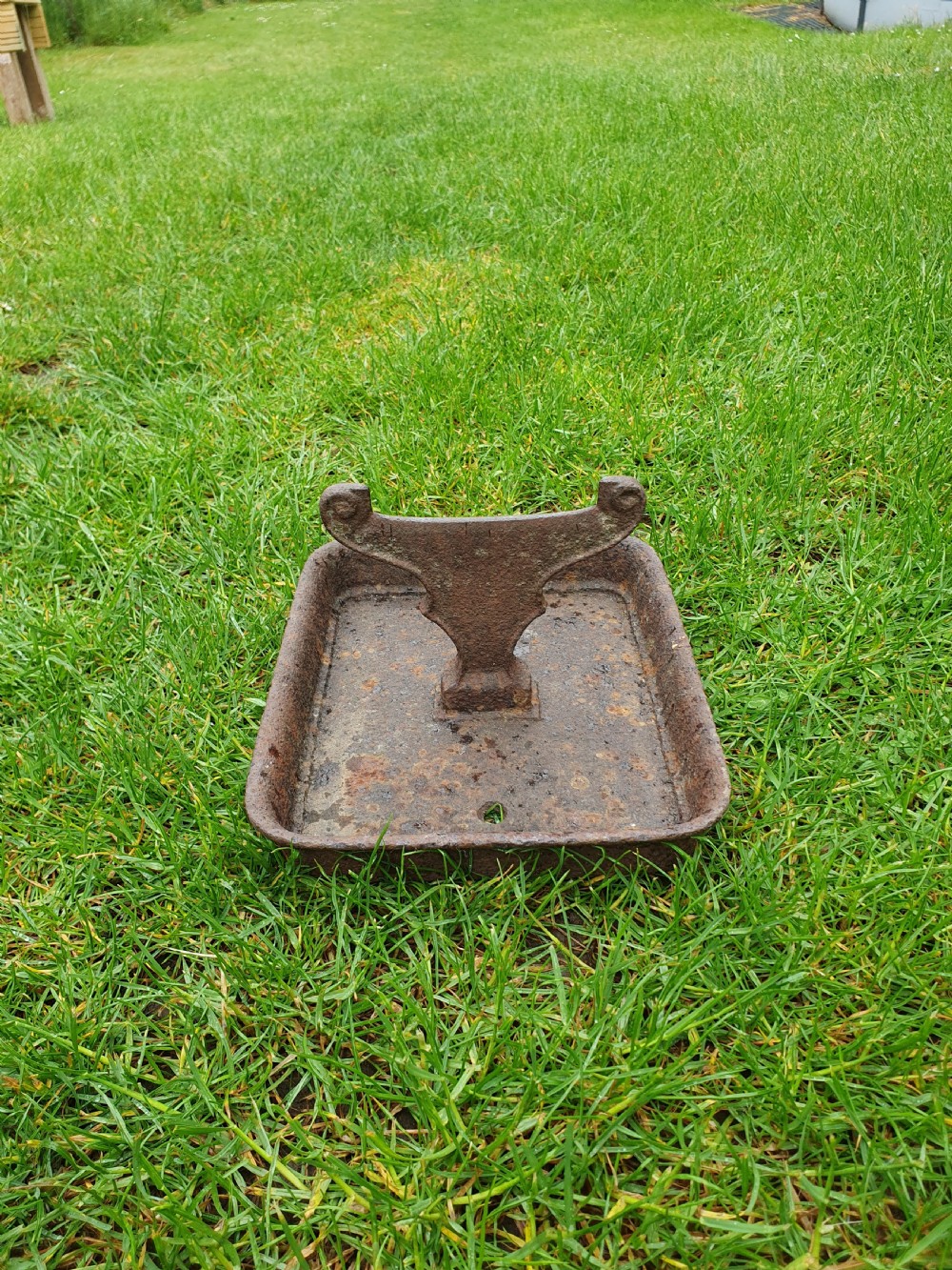 A late nineteenth-century cast iron boot scraper featuring a rectangular drip tray base and a scroll-detailed scraping blade with heavy rusted patina. View VII