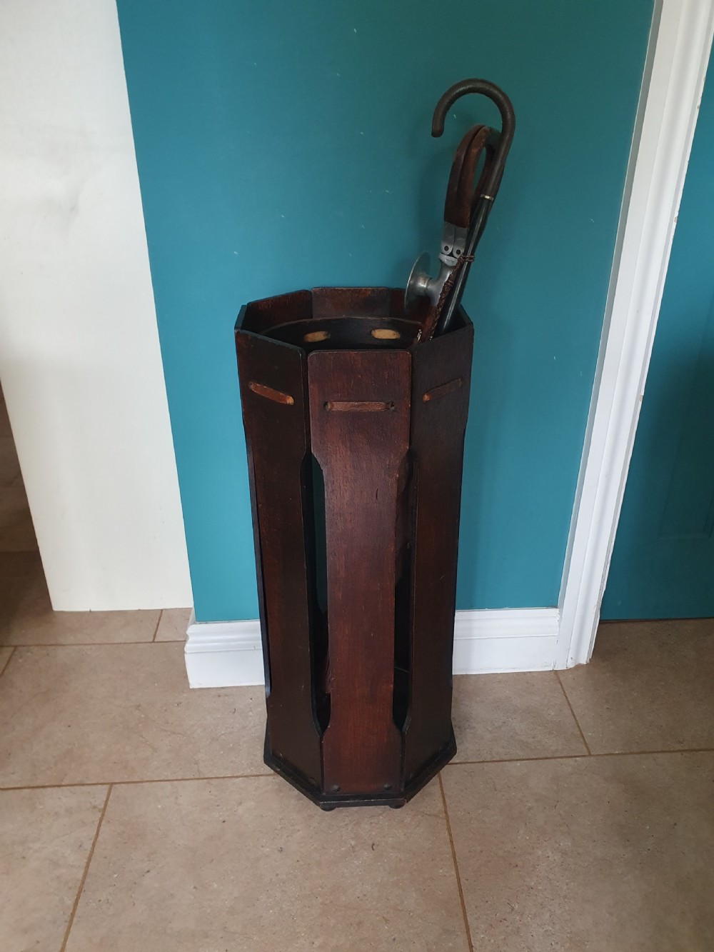 An early 20th-century dark wood octagonal stick stand featuring slatted vertical panels and an internal circular divider ring.