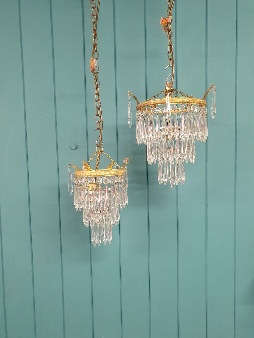 A pair of small early 20th-century gilded brass chandeliers featuring cascading tiers of crystal glass spikes.