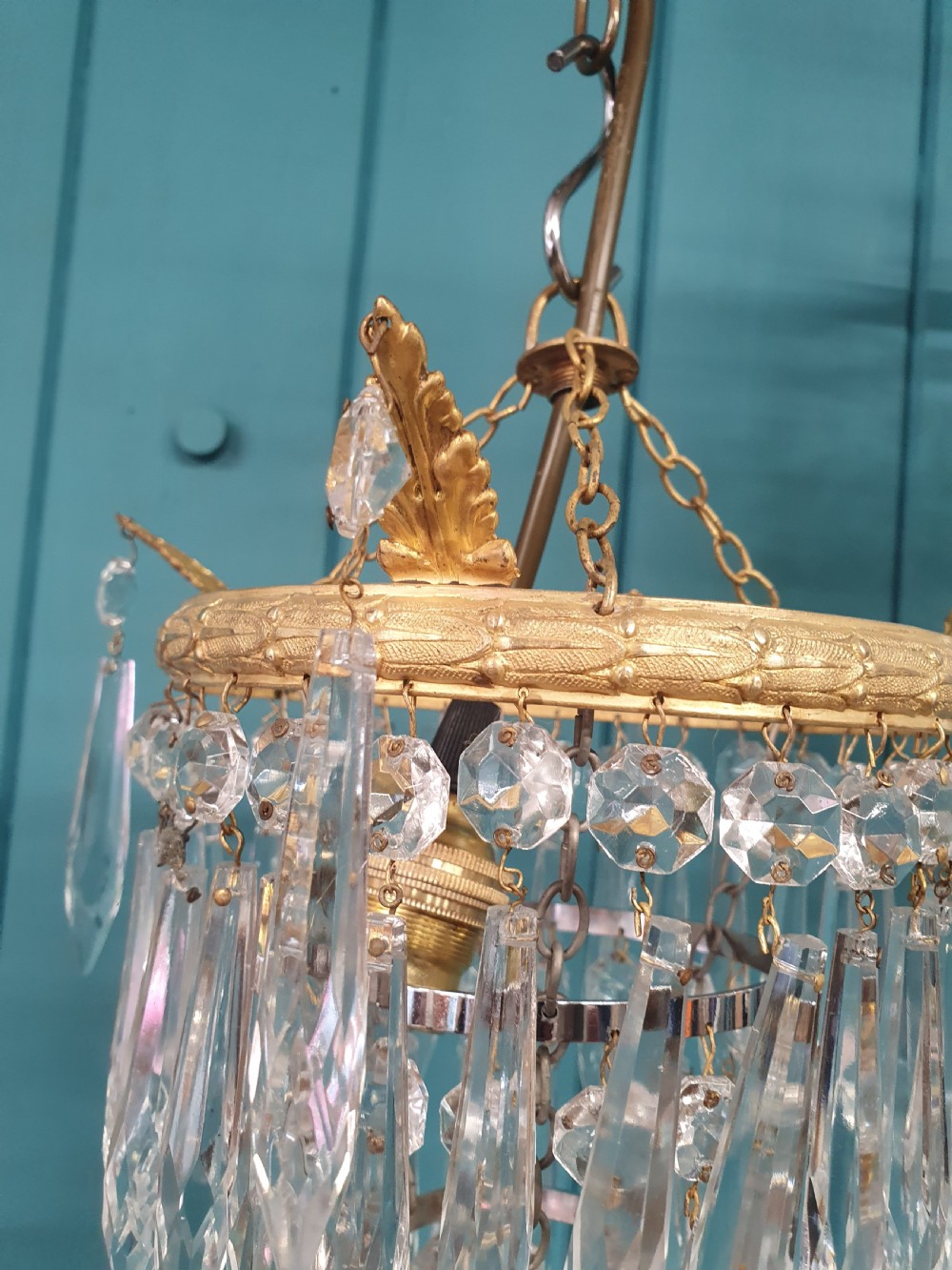 A pair of small early 20th-century gilded brass chandeliers featuring cascading tiers of crystal glass spikes. View II