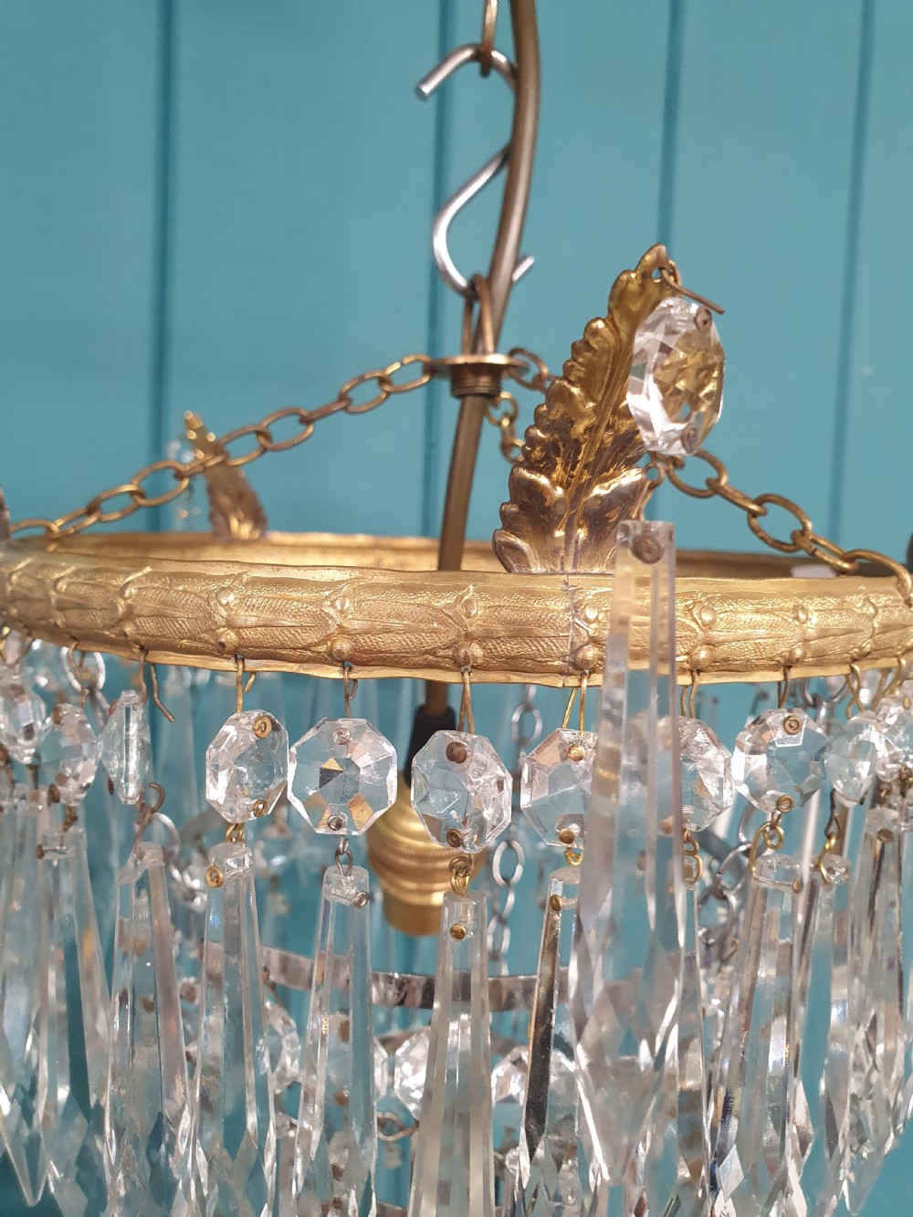 A pair of small early 20th-century gilded brass chandeliers featuring cascading tiers of crystal glass spikes. View III