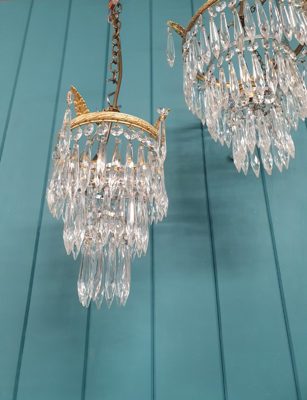 A pair of small early 20th-century gilded brass chandeliers featuring cascading tiers of crystal glass spikes. View IV