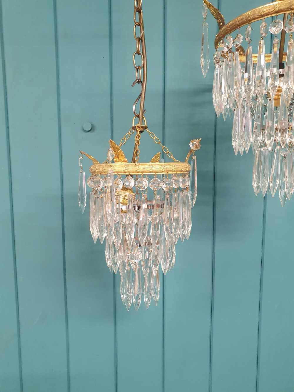 A pair of small early 20th-century gilded brass chandeliers featuring cascading tiers of crystal glass spikes. View V