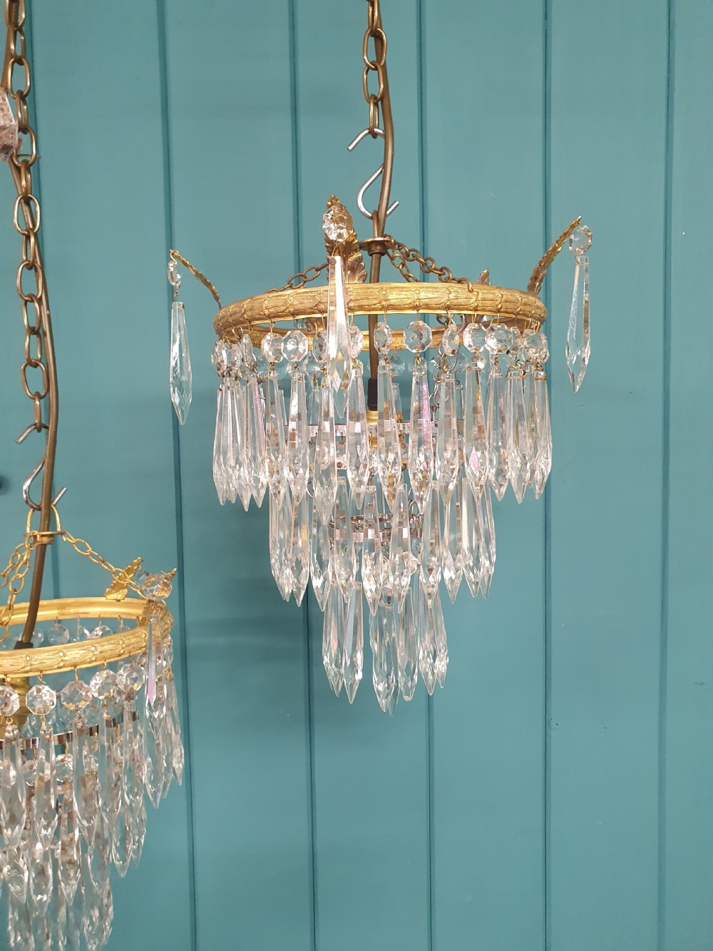 A pair of small early 20th-century gilded brass chandeliers featuring cascading tiers of crystal glass spikes. View VII