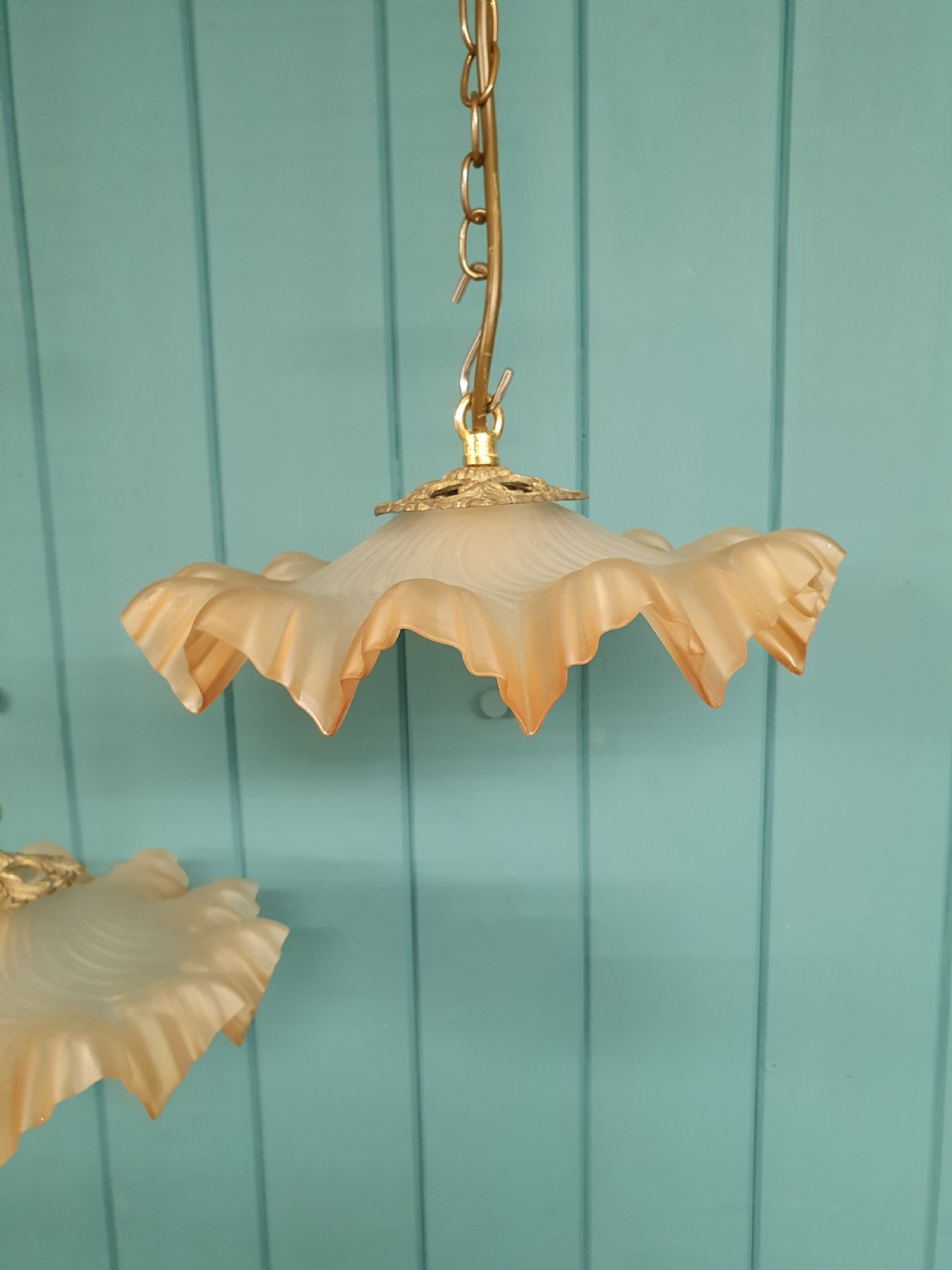 A pair of French pendant lights featuring peach frosted glass shades with ruffled fluted rims suspended from brass chains. View II