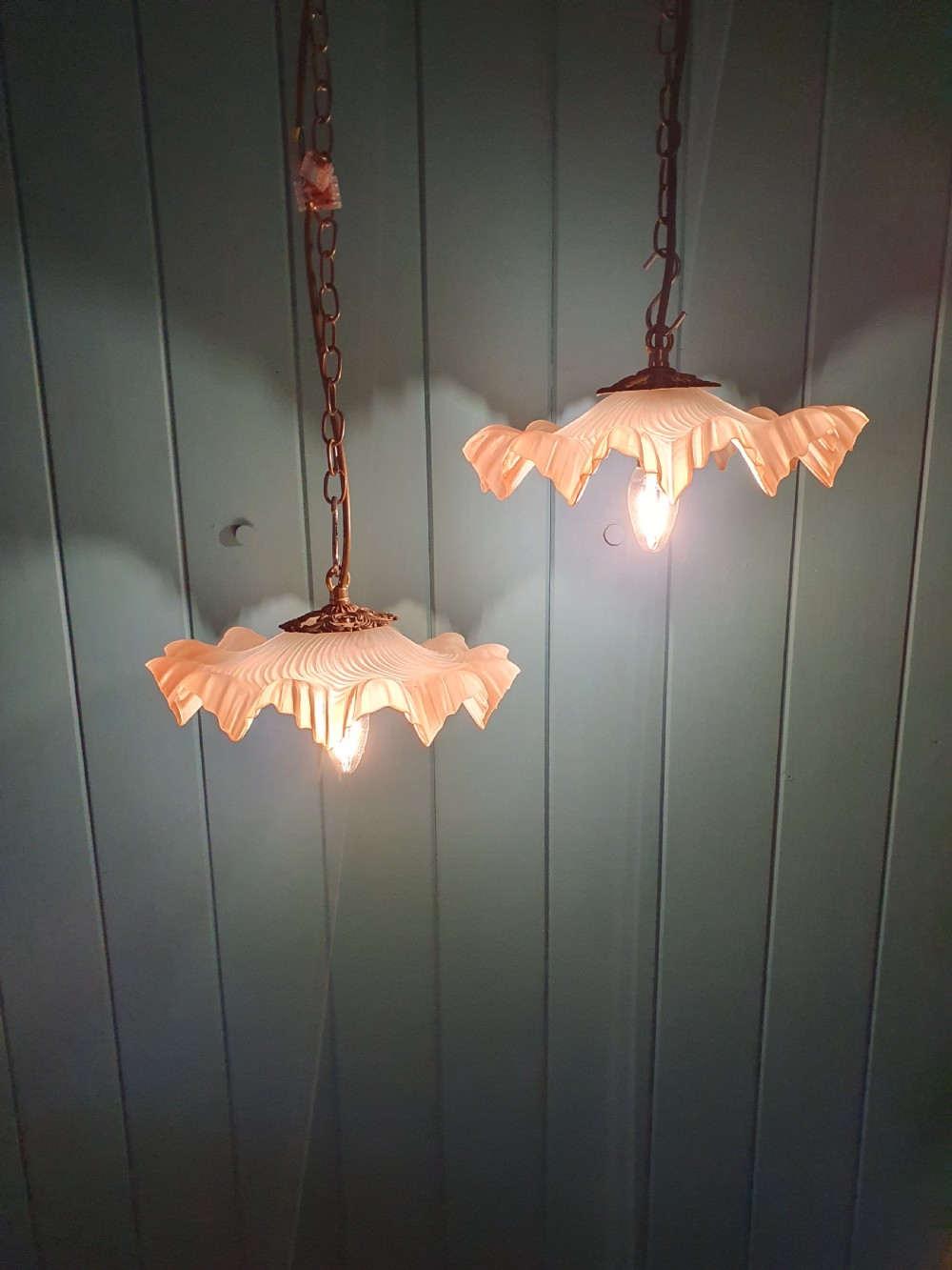 A pair of French pendant lights featuring peach frosted glass shades with ruffled fluted rims suspended from brass chains. View III