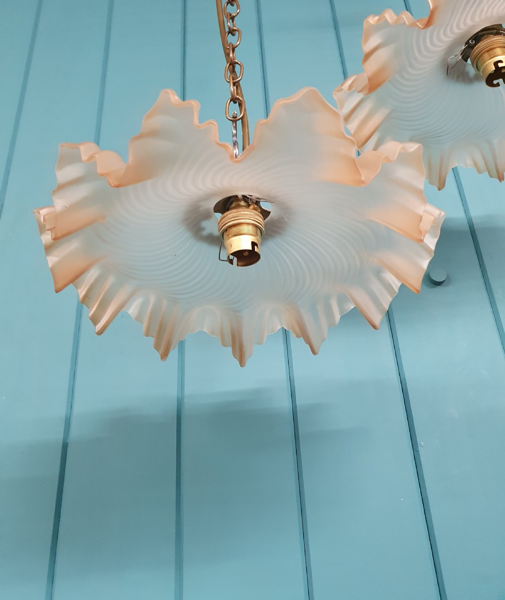 A pair of French pendant lights featuring peach frosted glass shades with ruffled fluted rims suspended from brass chains. View VI