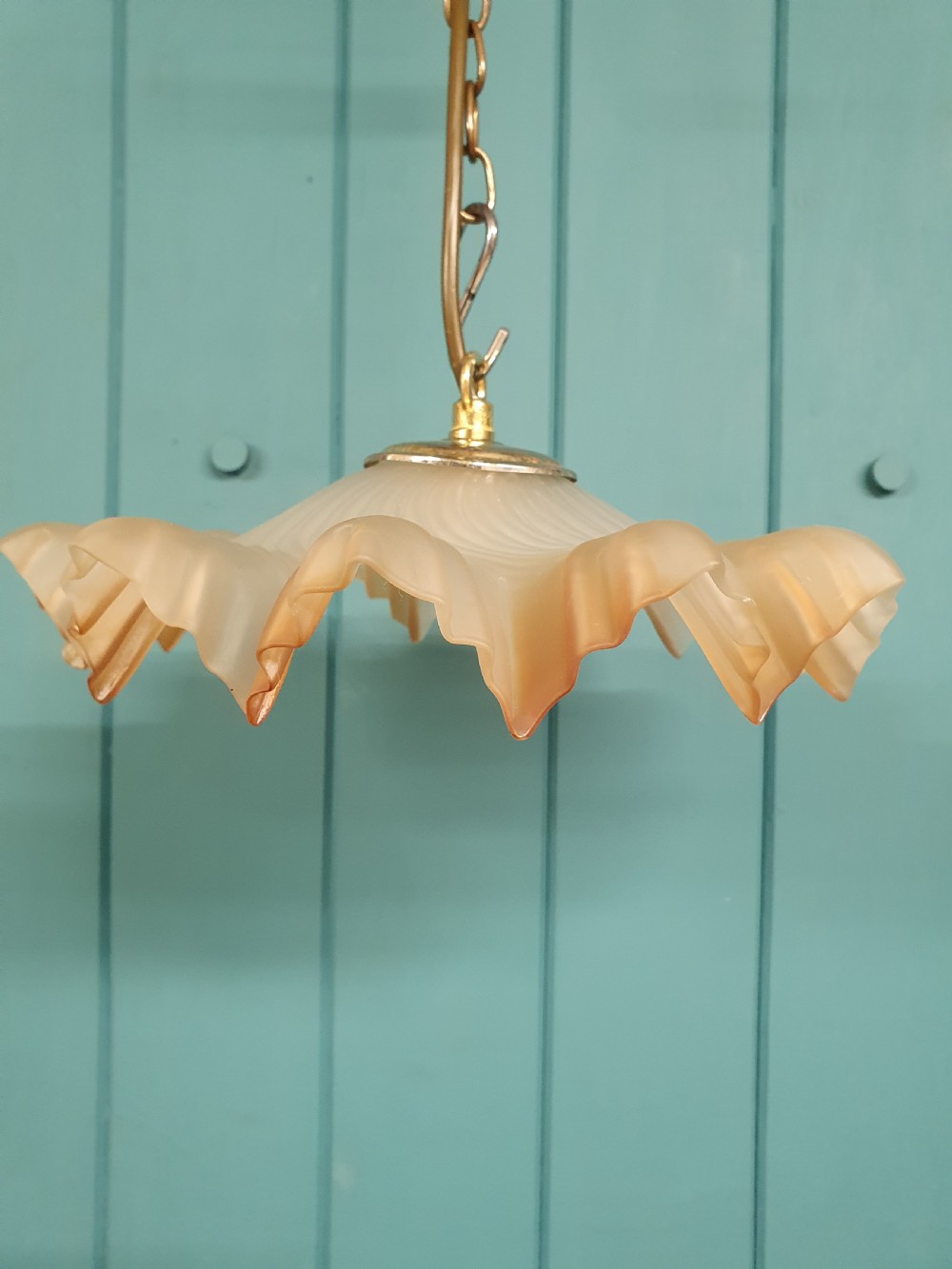 An antique French ceiling pendant featuring a frosted amber glass shade with a ruffled frilled rim suspended from a brass link chain. View II