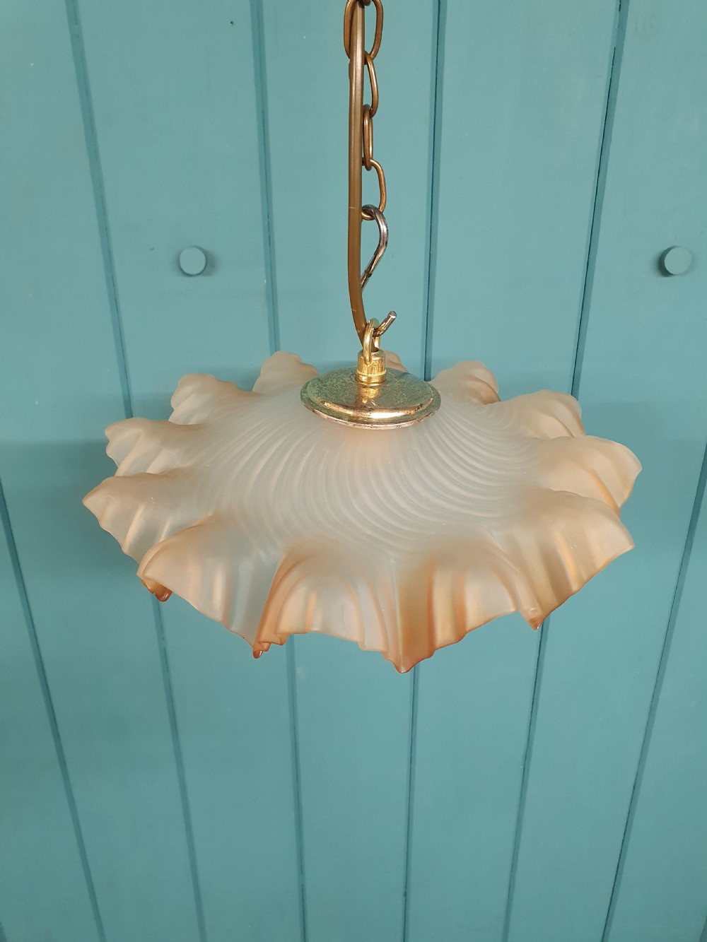 An antique French ceiling pendant featuring a frosted amber glass shade with a ruffled frilled rim suspended from a brass link chain. View III
