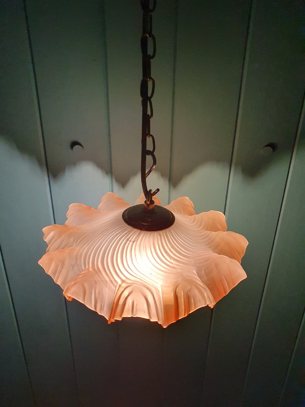 An antique French ceiling pendant featuring a frosted amber glass shade with a ruffled frilled rim suspended from a brass link chain. View V
