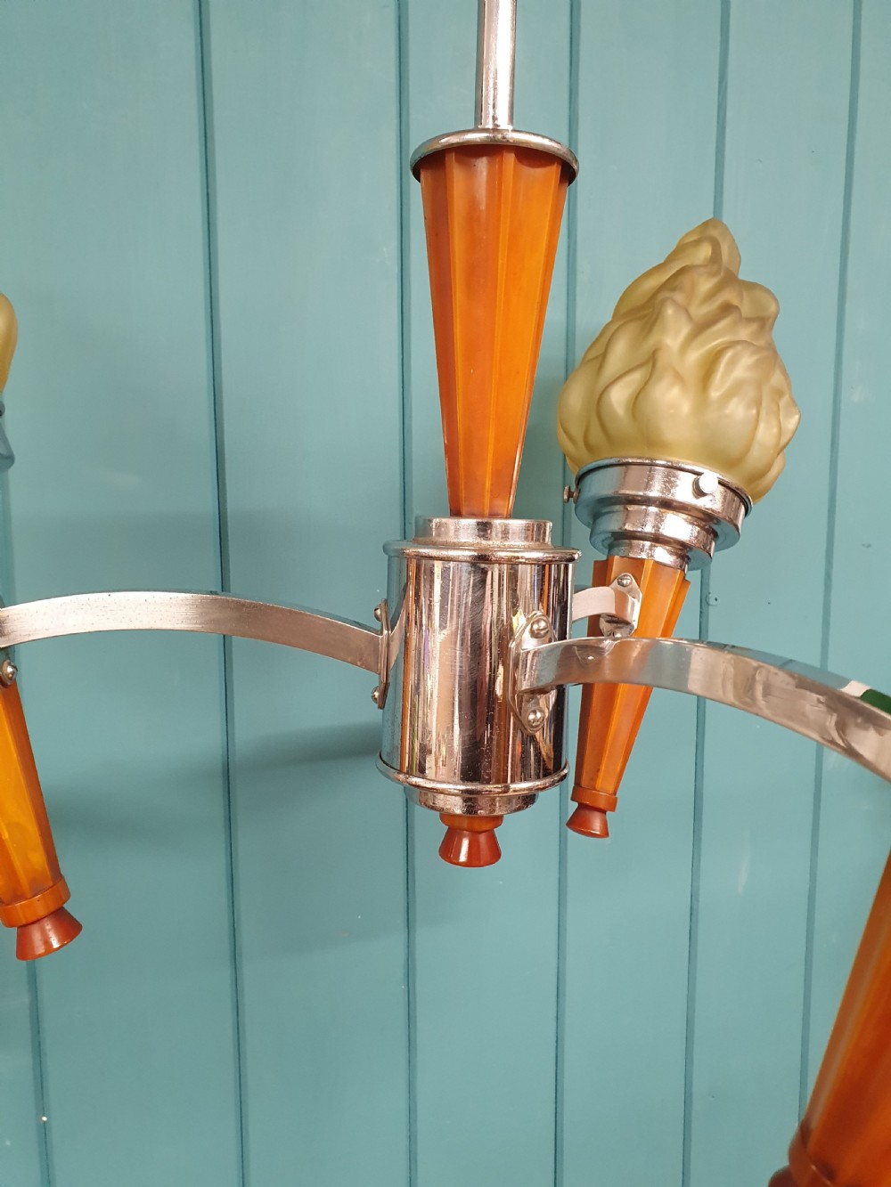 An Art Deco three-light chandelier featuring chrome stems, orange torch holders, and flame-shaped frosted glass shades. View III